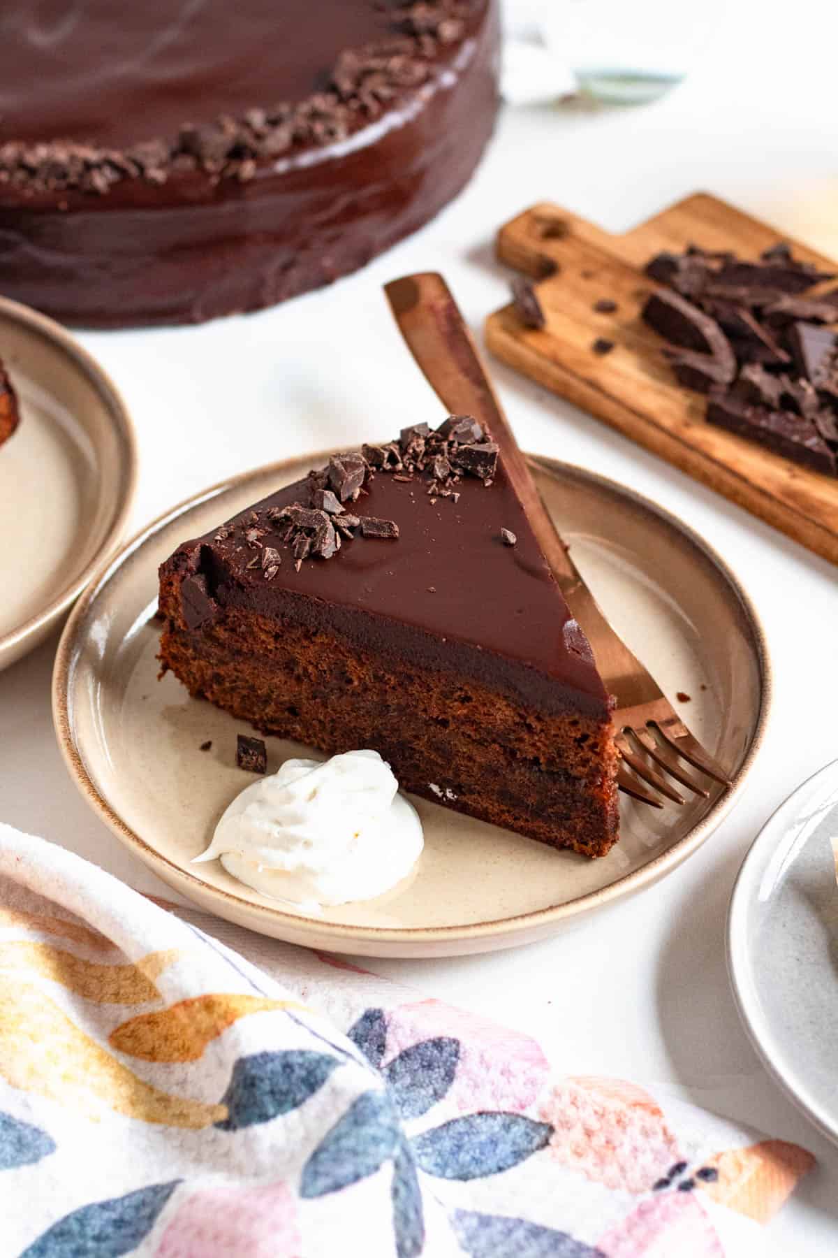 Slice of sacher torte cake on a plate with a fork resting on it. 