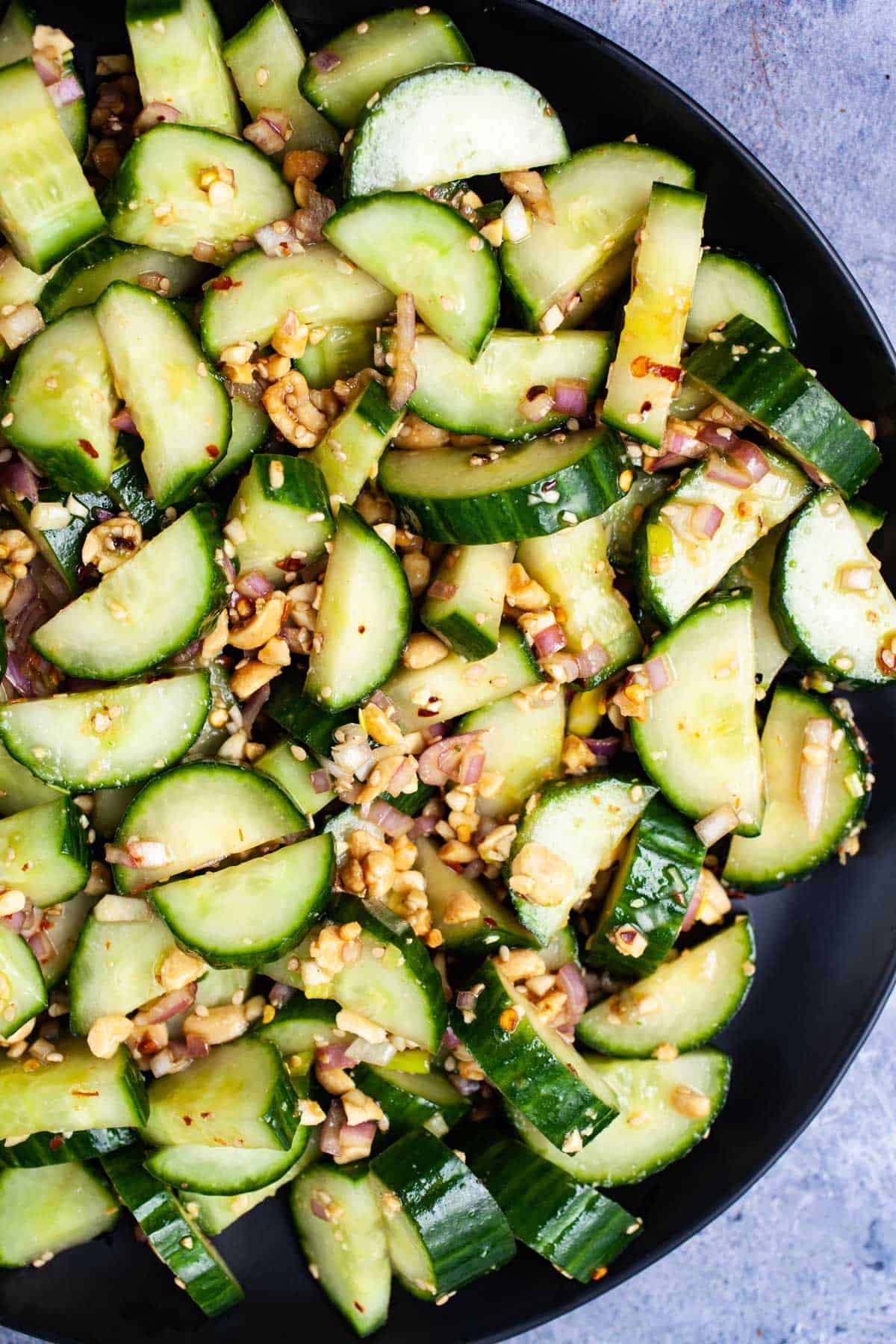 Serving dish of spiced cucumber salad with diced peanuts. 