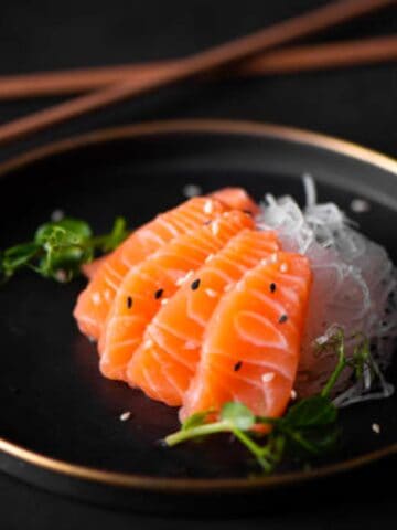 slices of fresh salmon with radish and soy sauce on plate