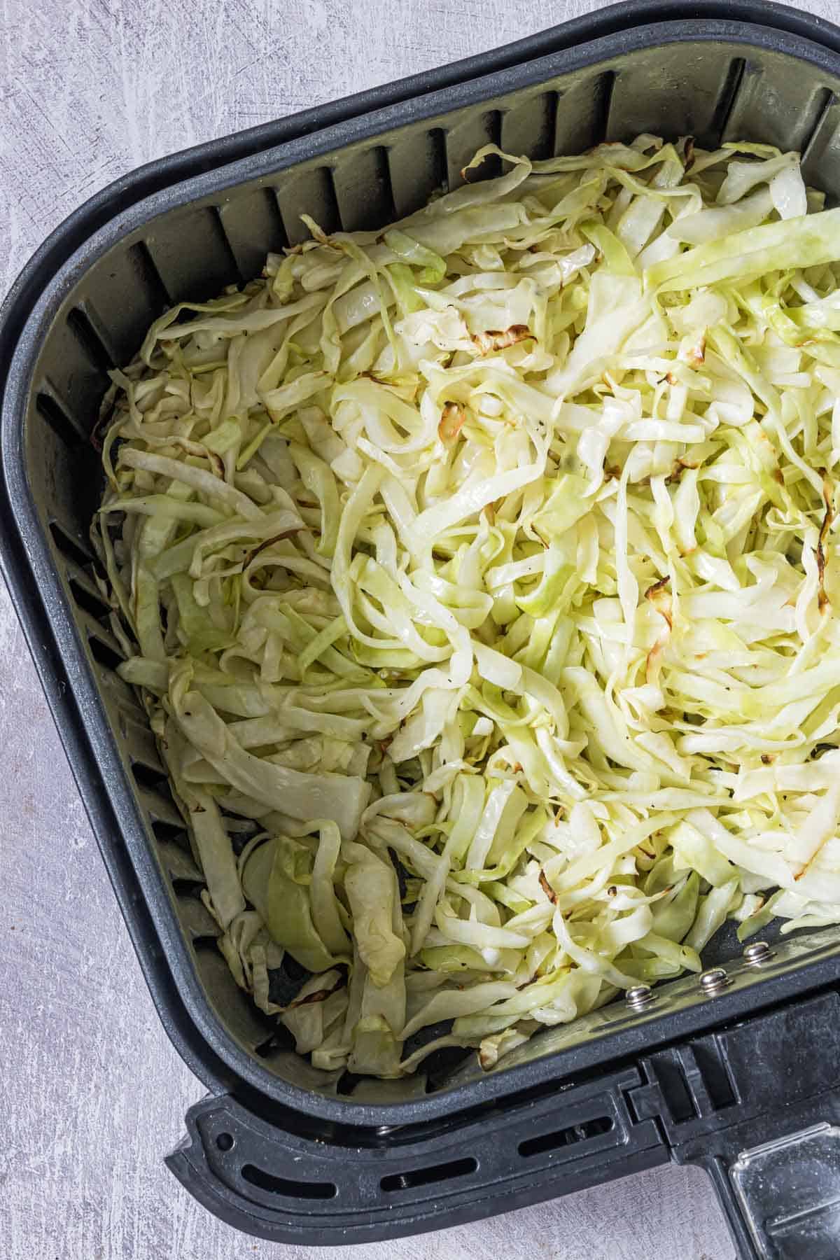 Shredded cabbage in an air fryer bucket. 