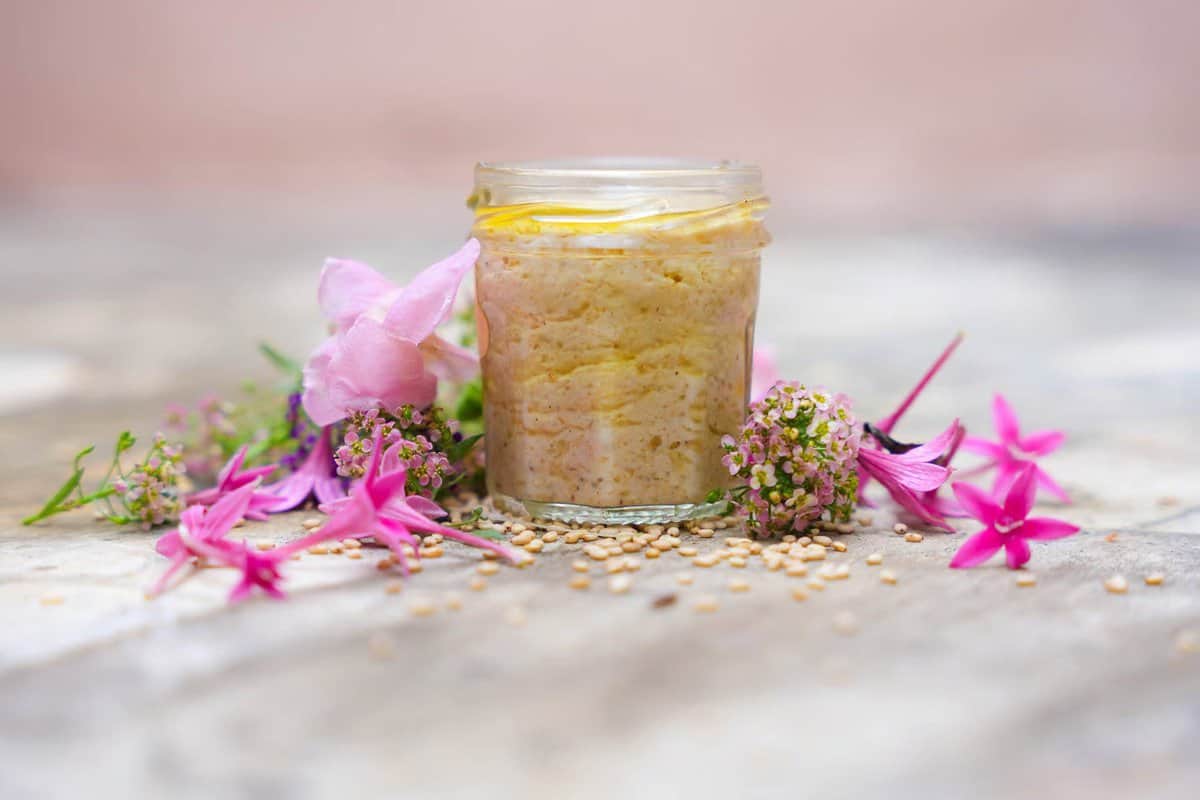Goma dressing in a small glass jar with small pink flowers garnished next to it. 