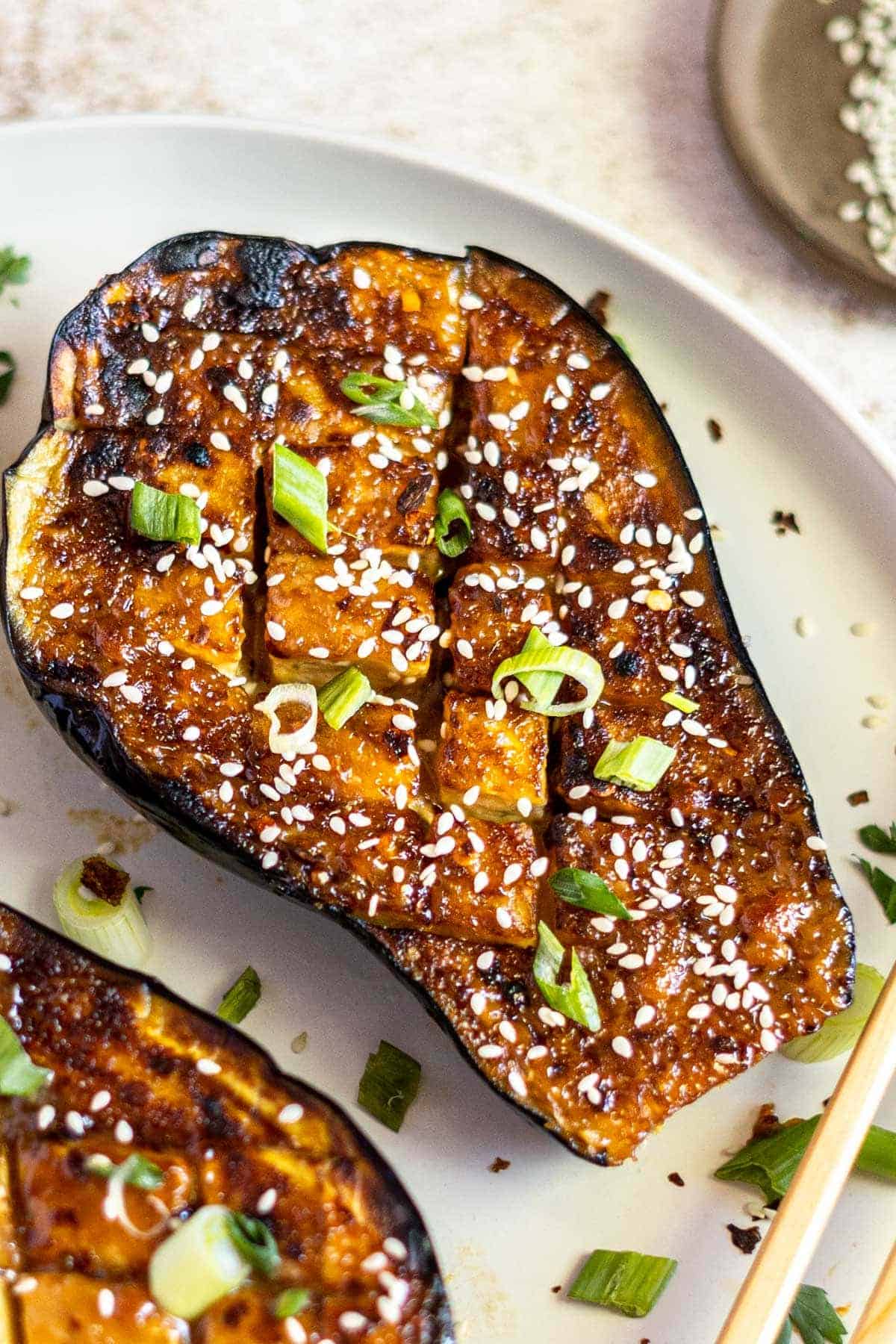 Half a miso eggplant garnished with sliced green onions and sesame seeds. 