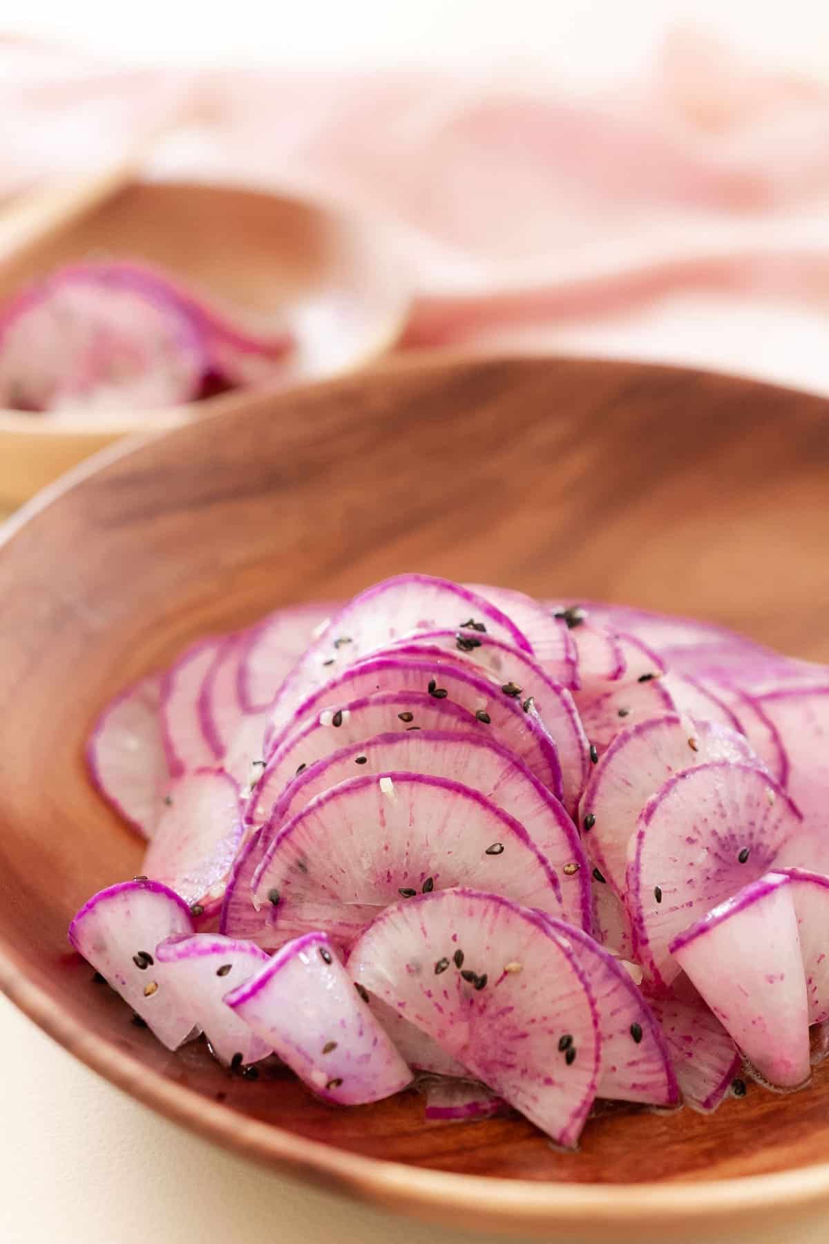 Thinly sliced purple daikon radishes topped with black sesame seeds. 