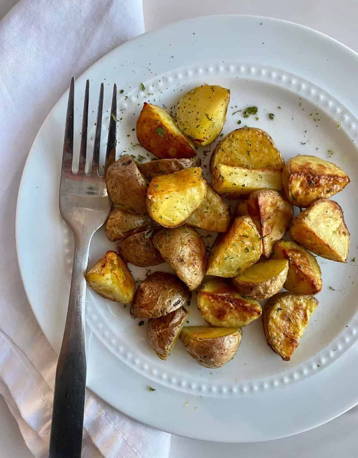 Fork laying next to Roasted mini potatoes. 