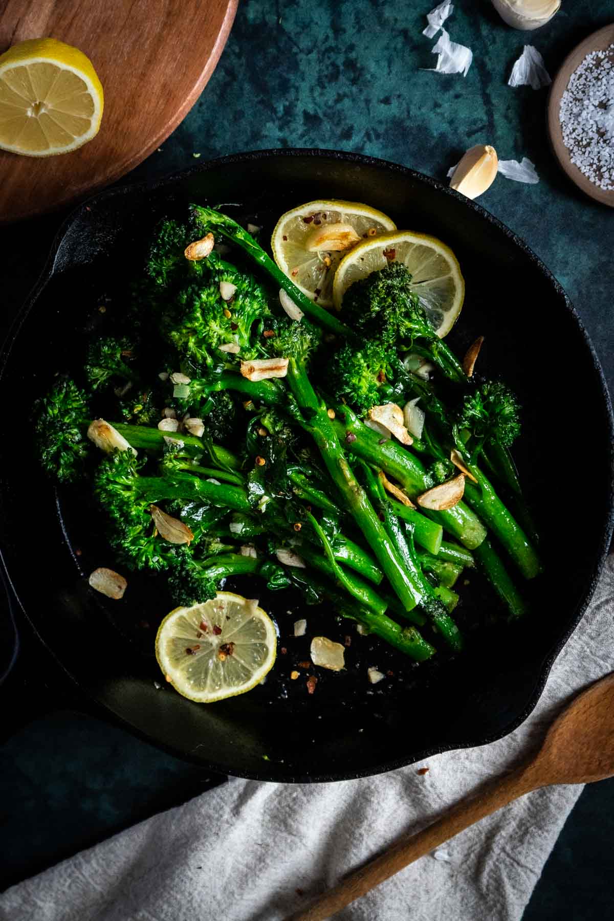 Lemon slices garnished on a plate filled with broccolini and garlic. 