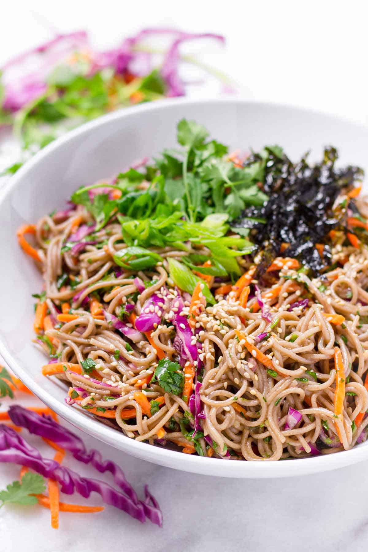 Cold soba noodle salad in a bowl topped with sesame seeds. 