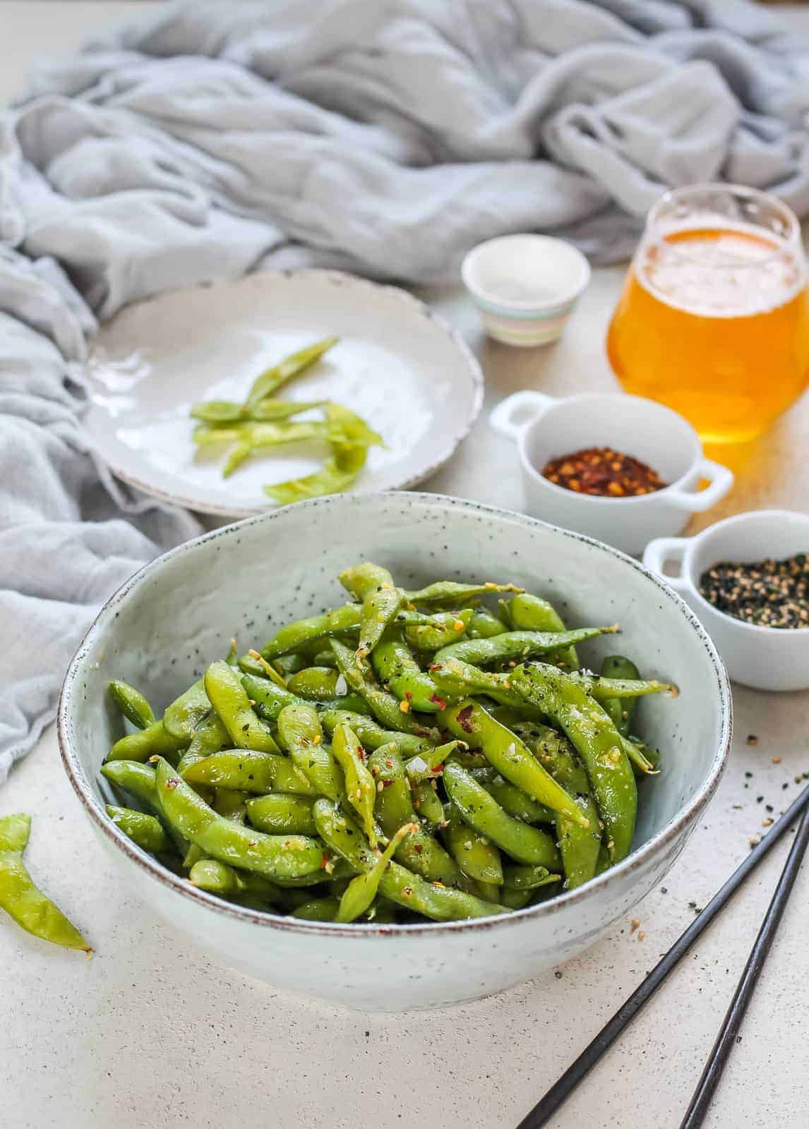 Spicy garlic edamame in a bowl with chopsticks resting next to it. 