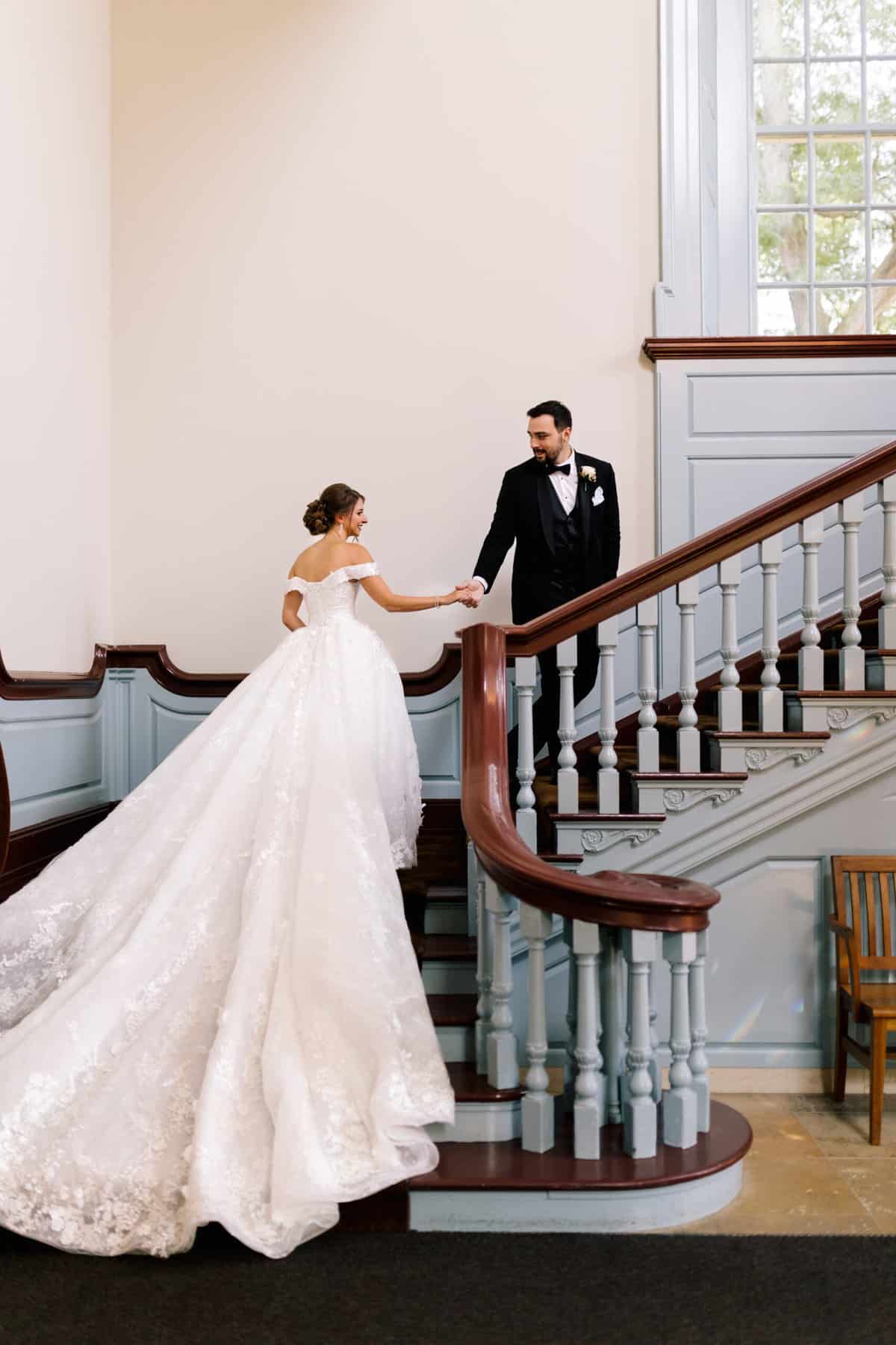 A groom leading a bride up a flight of stairs. 