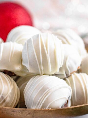 A pile of gingerbread truffles decorated in white chocolate drizzles.