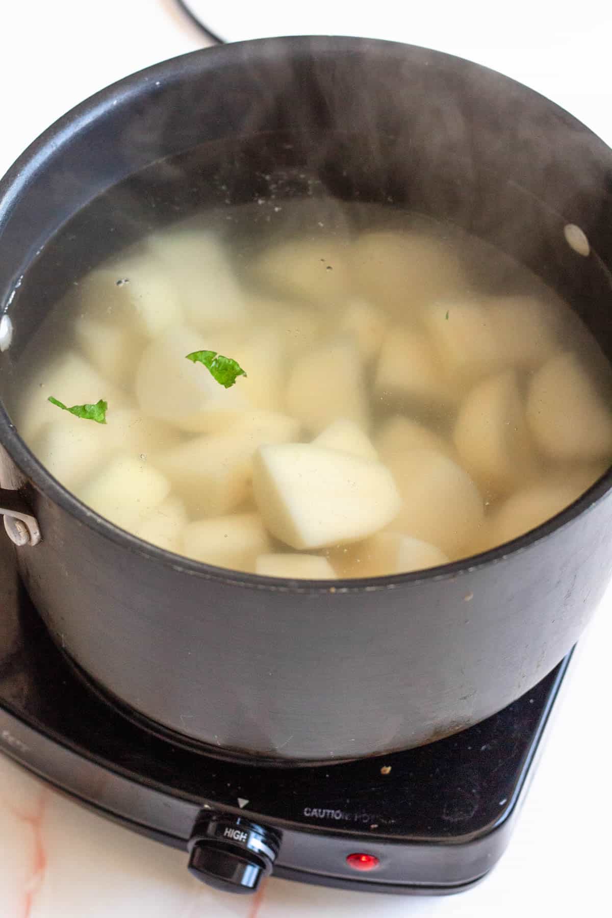 Peeled and cut potatoes boiling in a saucepan. 