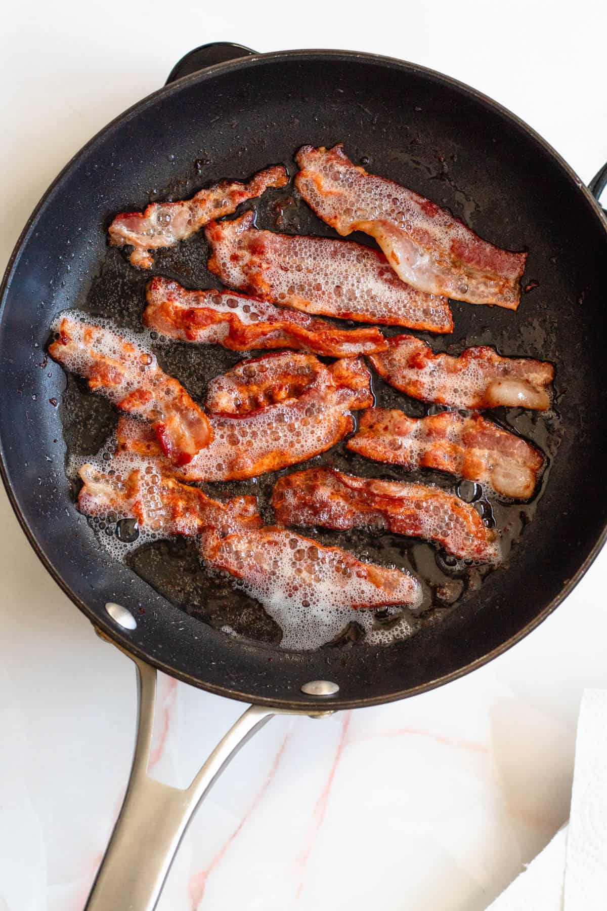 Crispy bacon frying in a skillet. 