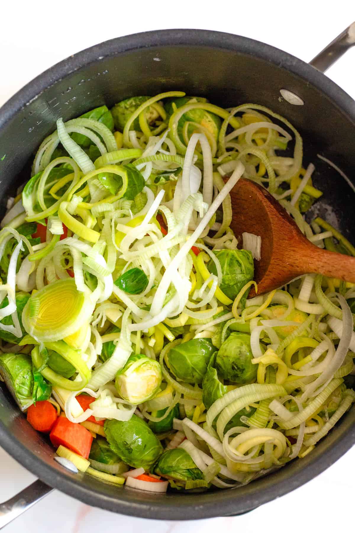 Leeks, Brussels sprouts and carrots sliced up and sauteeing in a pan. 