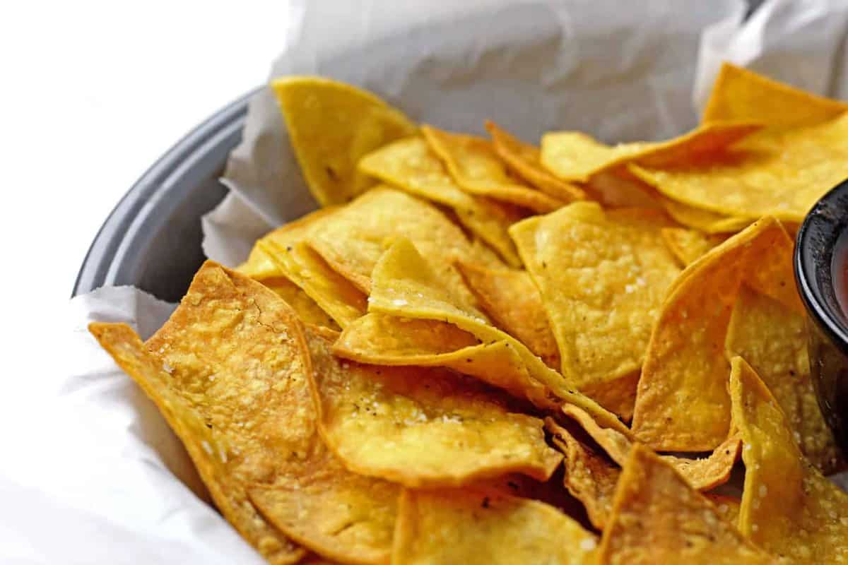 Air fryer tortilla chips in a bowl covered in parchment paper.