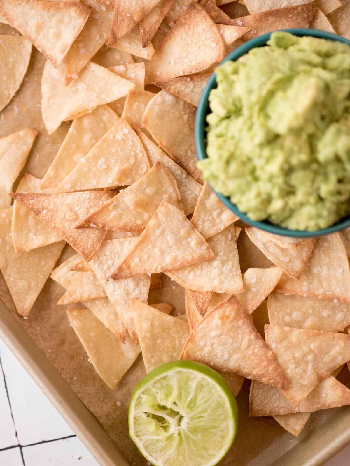Homemade baked tortilla chips next to a bowl of guacamole. 