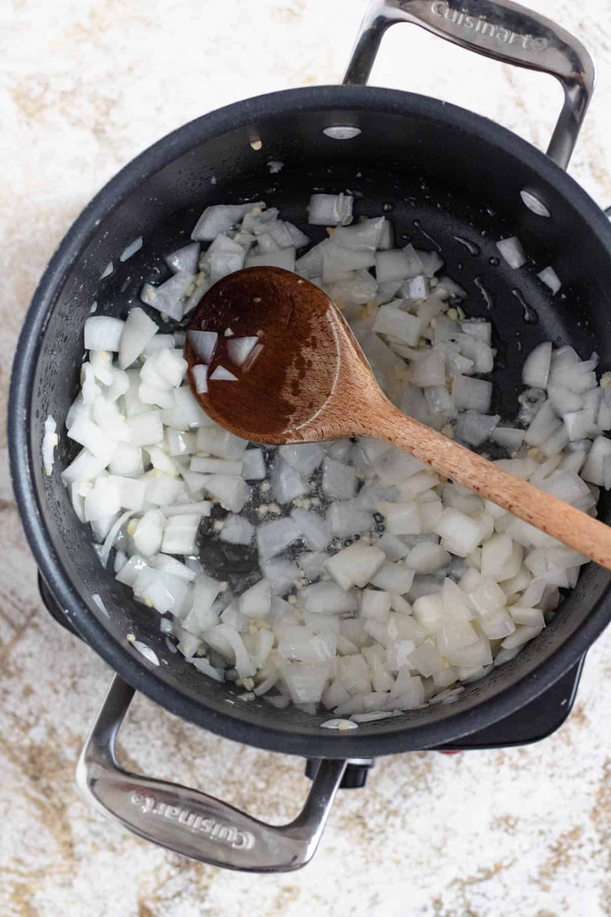 Diced onions and minced garlic sauteeing in a saucepan. 