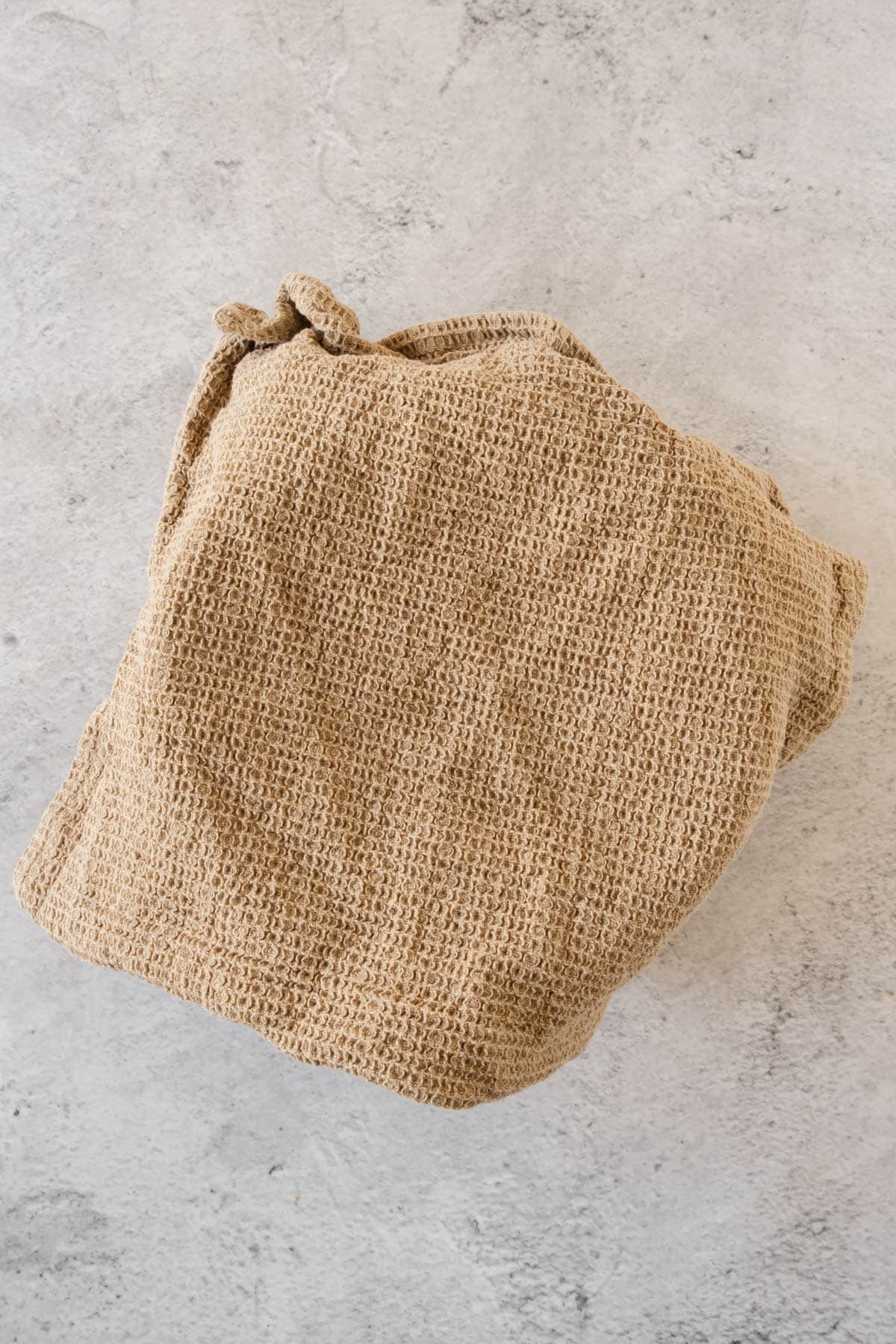 A kitchen towel covering the brioche bread dough in a mixing bowl as it rises. 