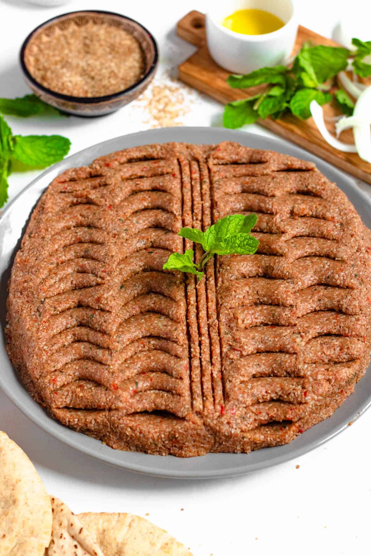 Plate of kibbeh nayeh with a mint leaf garnished on top. 