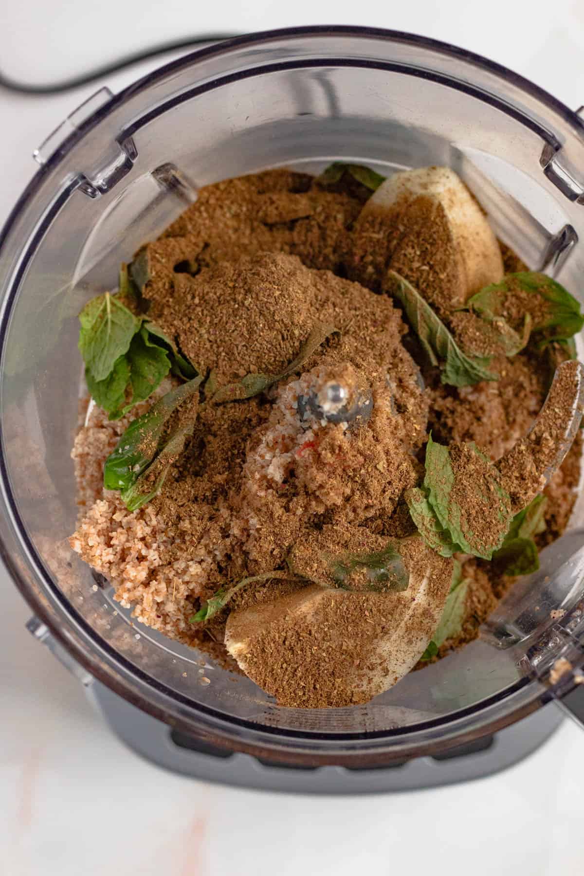 Food processor with fresh mint and basil, seasonings and onion added to the meat mixture. 