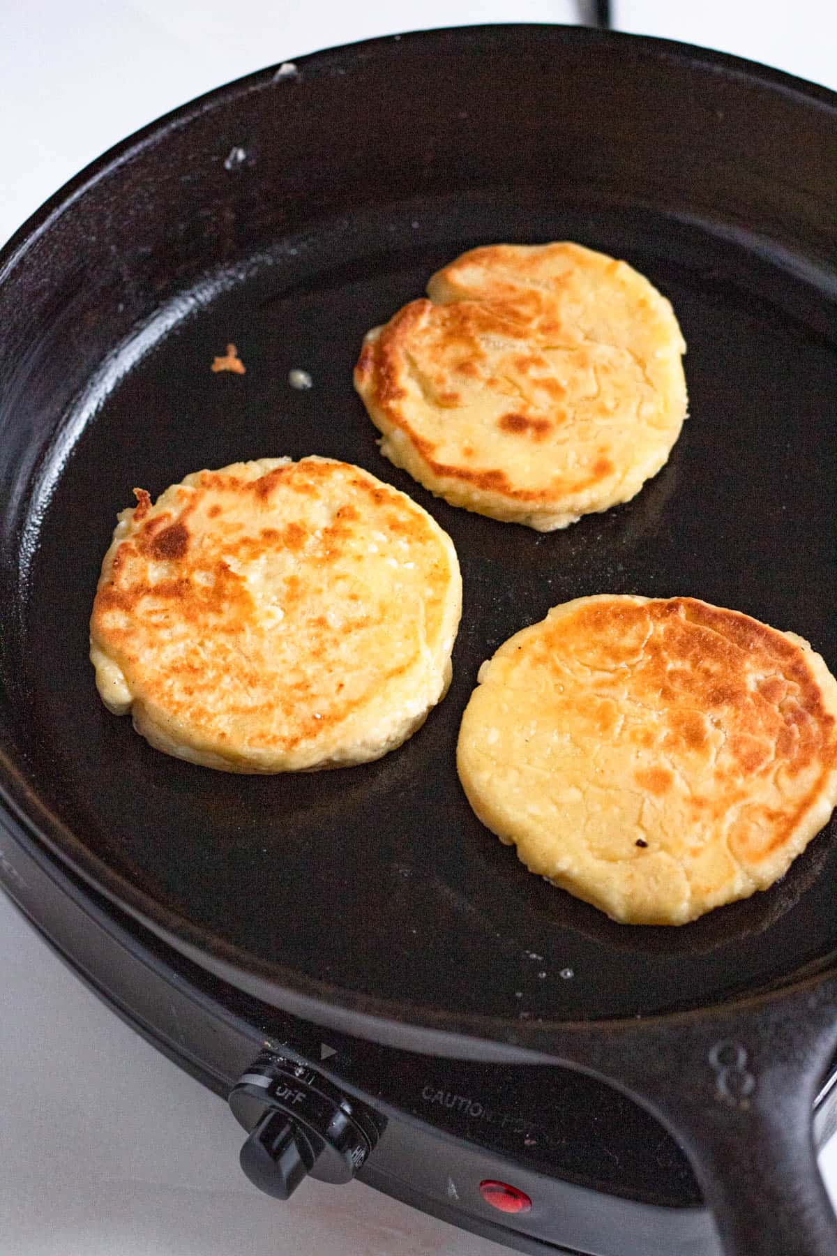 Cast iron pan with golden fried Syrniki. 