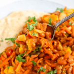 Pinterest image of a spoonful of chakalaka coming from a plate.