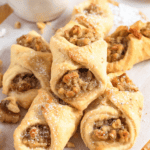 Pinterest image of a stack of walnut cookies on a parchment paper-covered cutting board with a small bowl of walnuts next to it.
