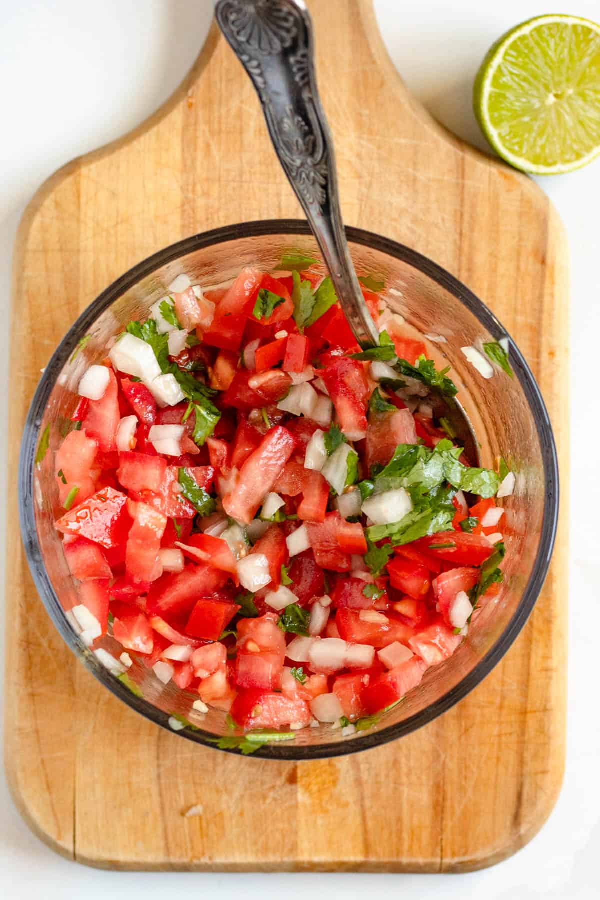 Pico de gallo mixed in a bowl with a spoon resting in it. 