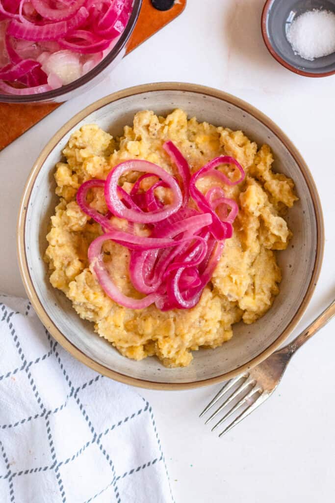Top view of a bowl of mangu topped with red onions. 