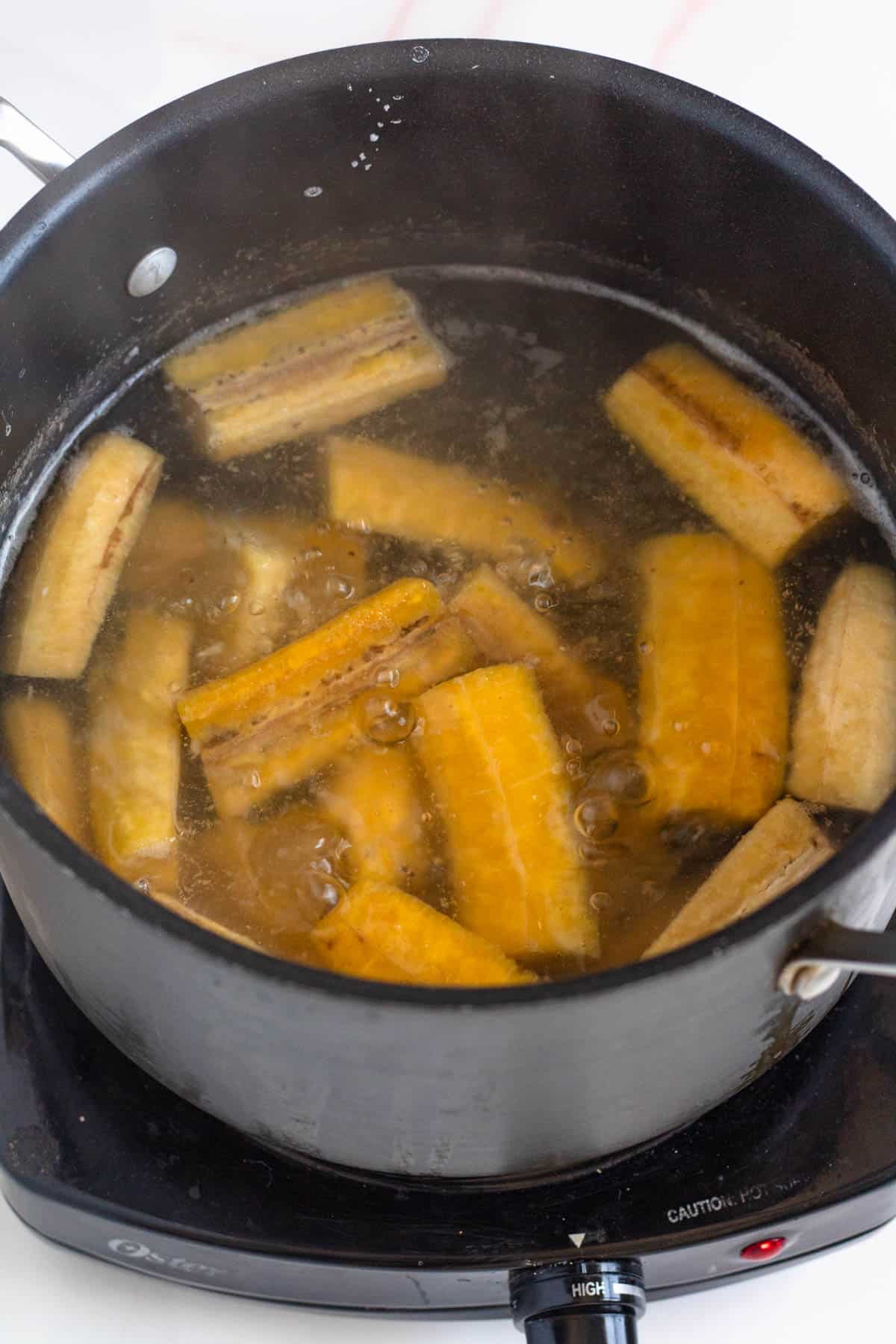 Green plantains boiling in a saucepan. 