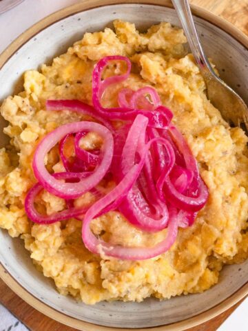 A bowl of mangu with pickled red onions on top