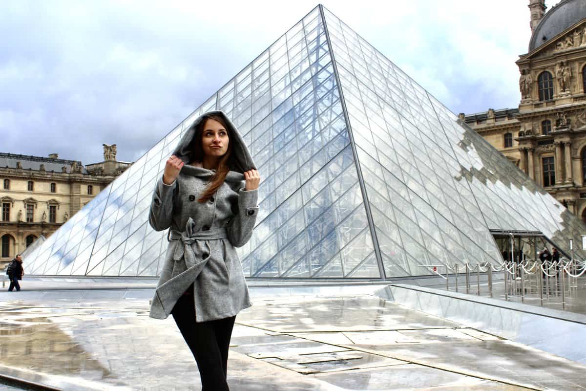 Alexandria posing in front of a glass pyramid.