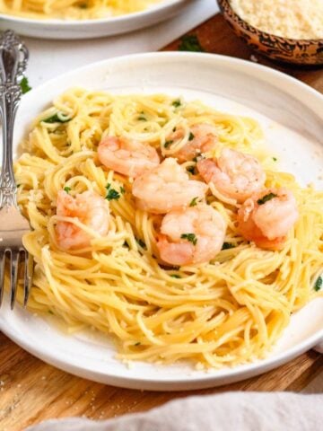 A plate of Instant Pot shrimp scampi on top of angel hair pasta with a fork.
