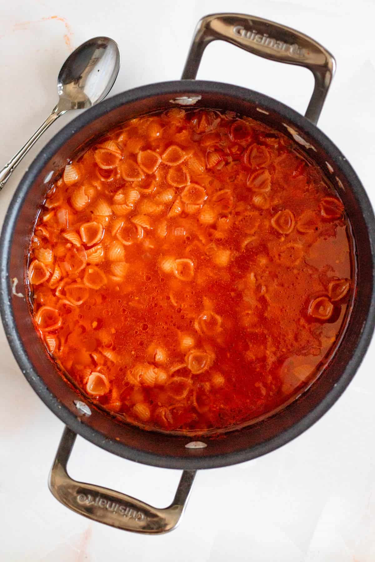 Sopa de conchitas with cooked shell pasta in a large black pot.