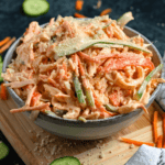 Pinterest image of Kani Salad in a bowl, sitting on a cutting board.