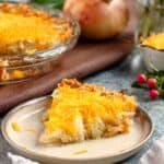 A slice of Onion Pie on a plate with the large pie behind it