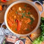 A rich West African peanut stew with meat, potatoes, and peppers, garnished with cilantro with a pack of taste africa beside it.