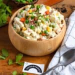 A creamy Ensalada de Pollo served in a wooden bowl, garnished with cilantro.