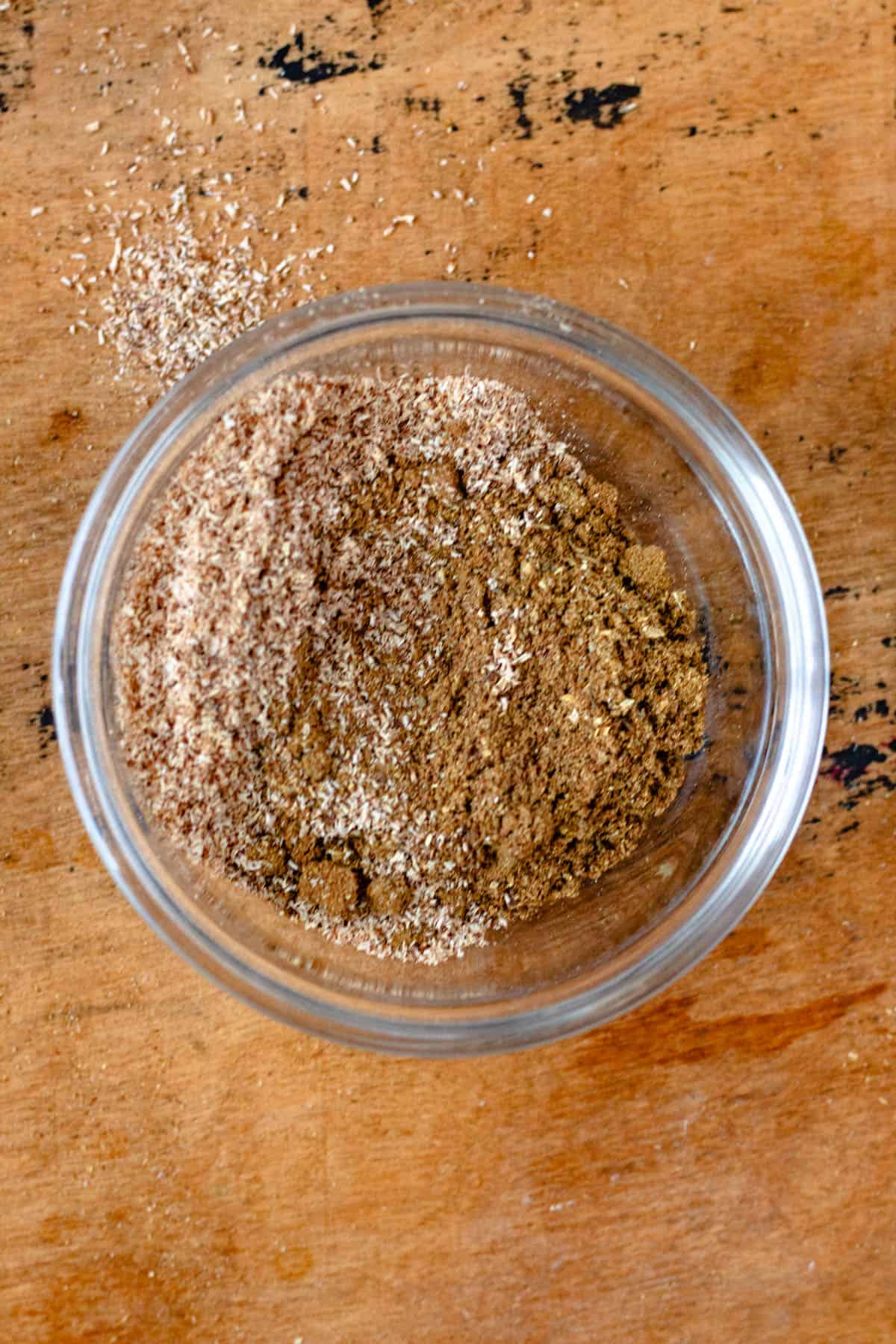 Grated nutmeg is added to the bowl of ground spices.