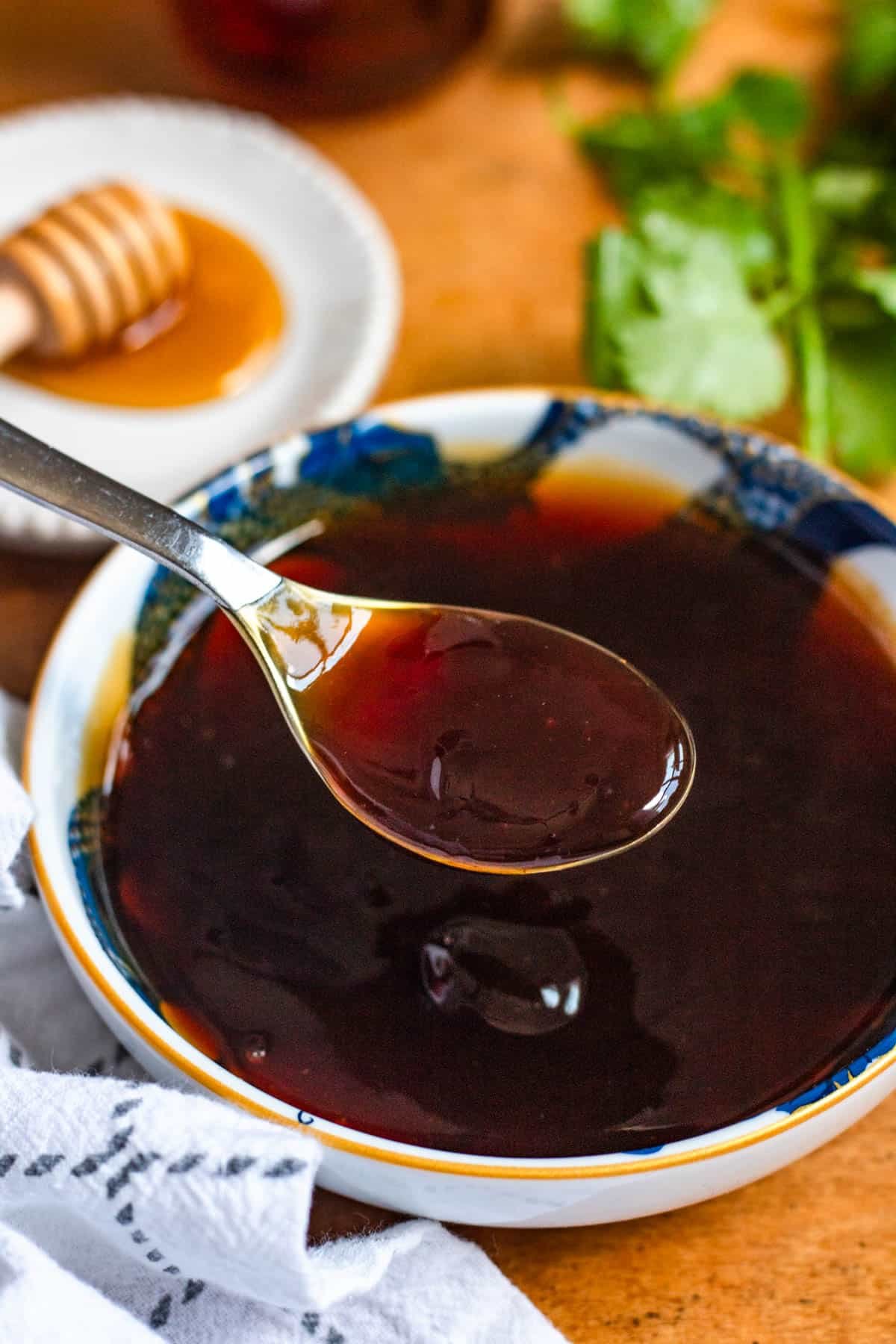 A spoonful of dark 3 ingredient stir fry sauce held over a bowl of the same sauce.
