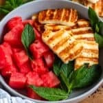 A vibrant bowl of grilled halloumi, juicy watermelon, and fresh mint leaves.