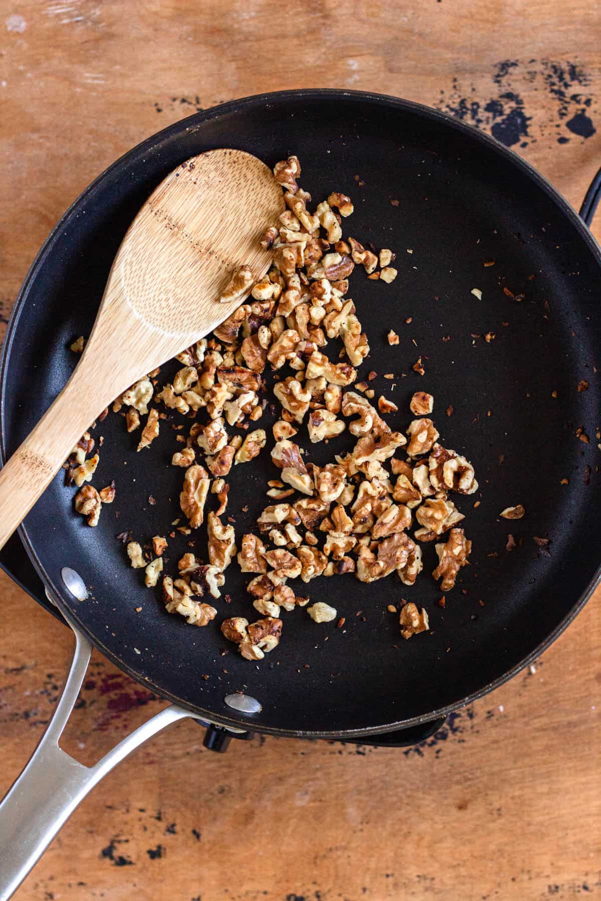 Walnut pieces were toasted in a pan using a wooden spatula.