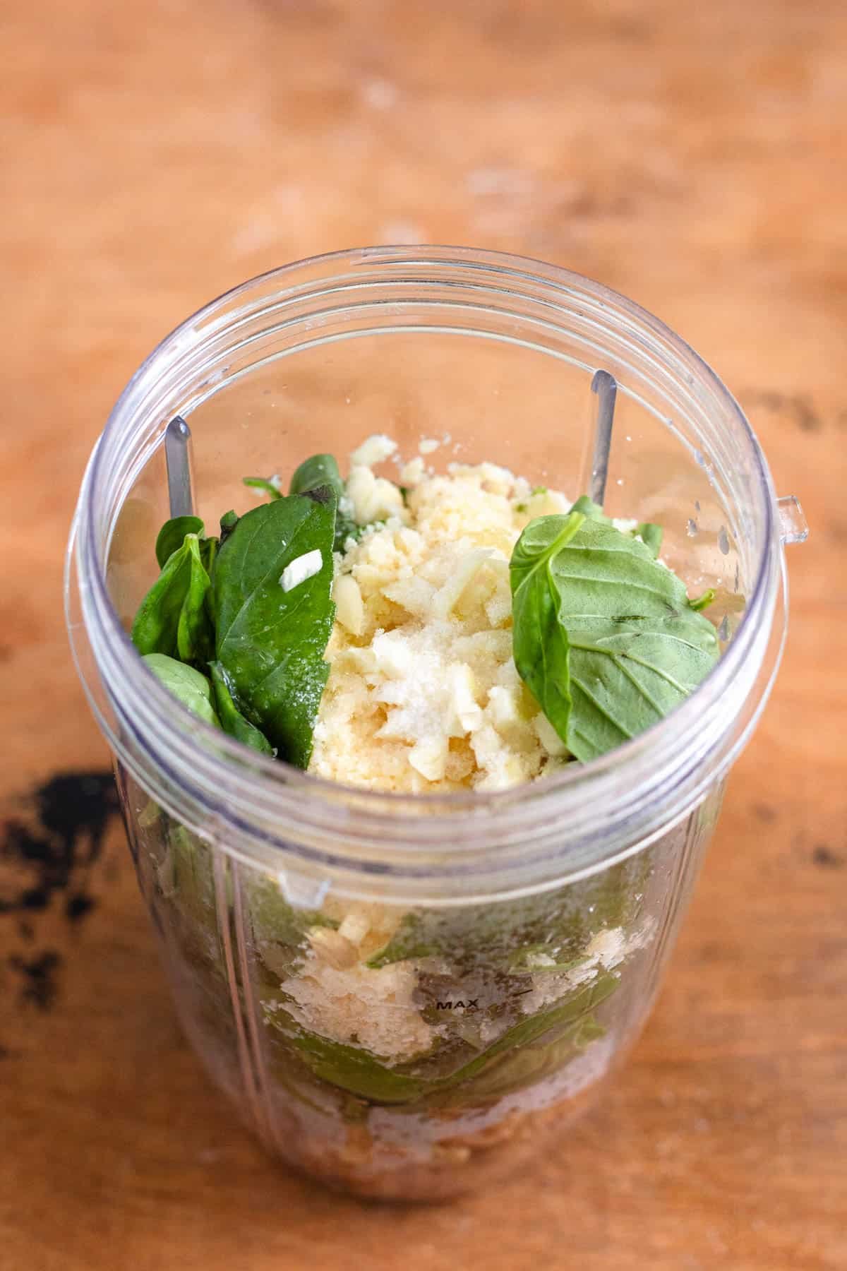 All the ingredients, including basil, lemon, cheese, and olive oil, were placed in the Nutribullet for blending.