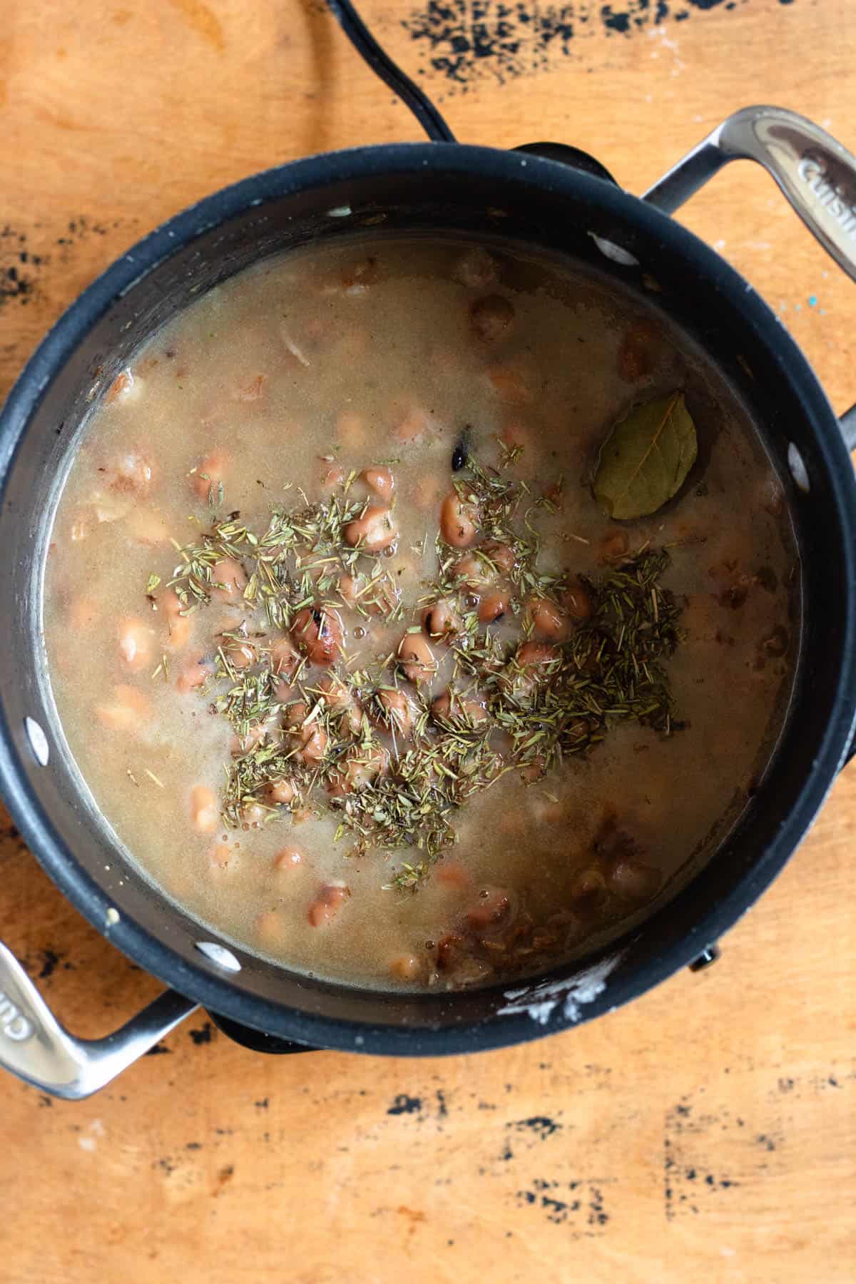 Chicken stock, beans, and herbs were added into the pot of bacon and onion.