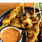 Pinterest image of Chicken Satay showing chicken skewers on a plate next to peanut sauce.