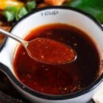 A cup of fajita sauce with a spoonful lifted above it.