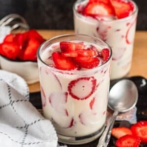 Glasses filled with creamy Fresas Con Crema mixed with fresh sliced strawberries.
