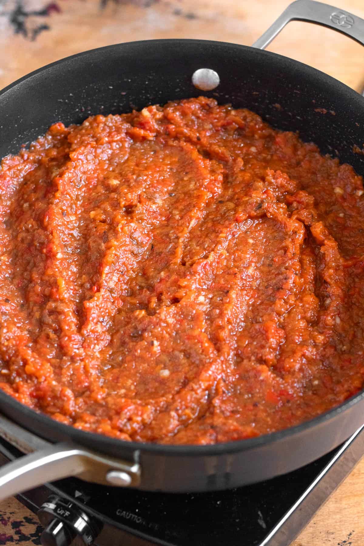 Pureed bell pepper and eggplant are being cooked down in a pan.