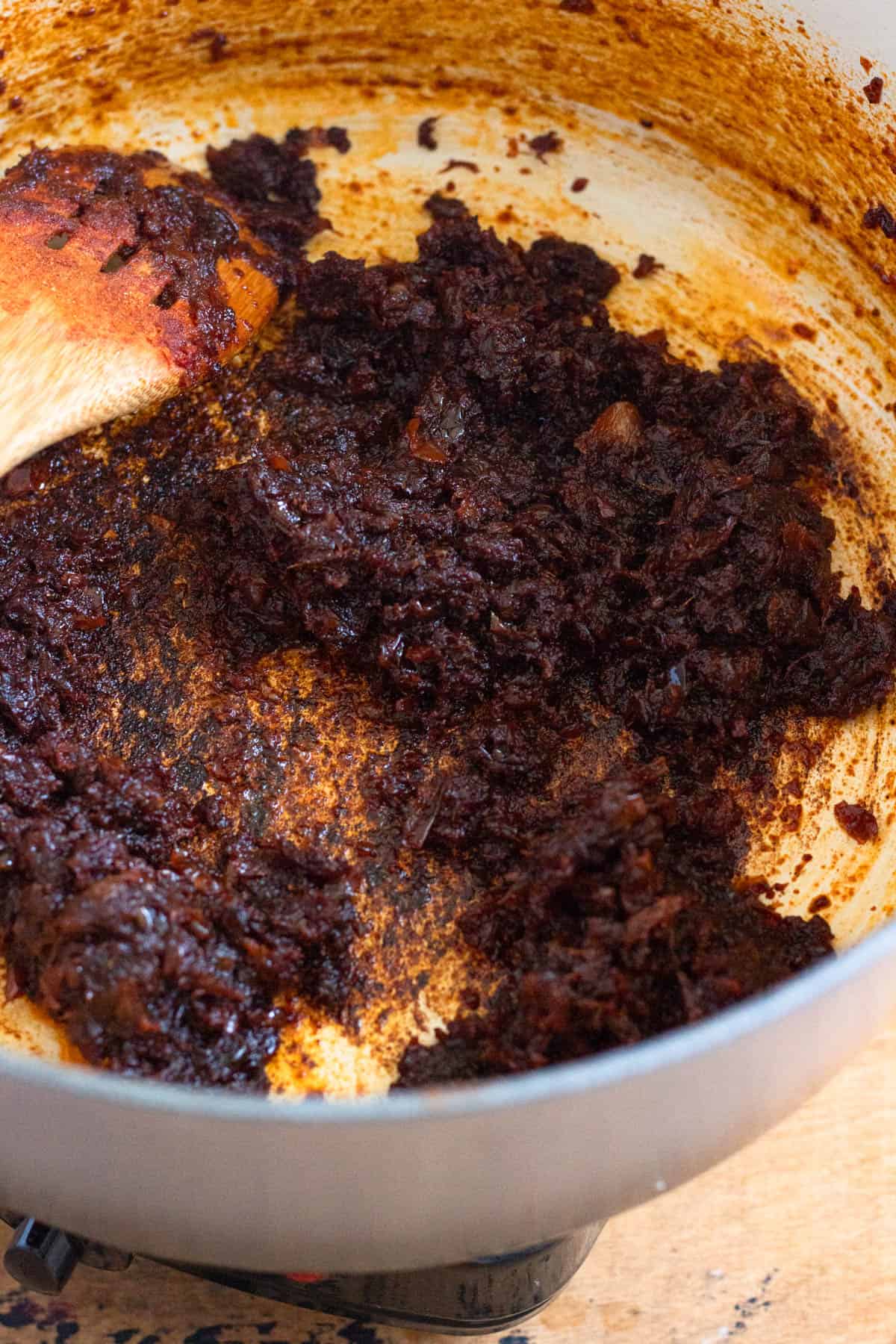 Berbere seasoning, cardamom, and ghee being added to the mixture in a Dutch oven.
