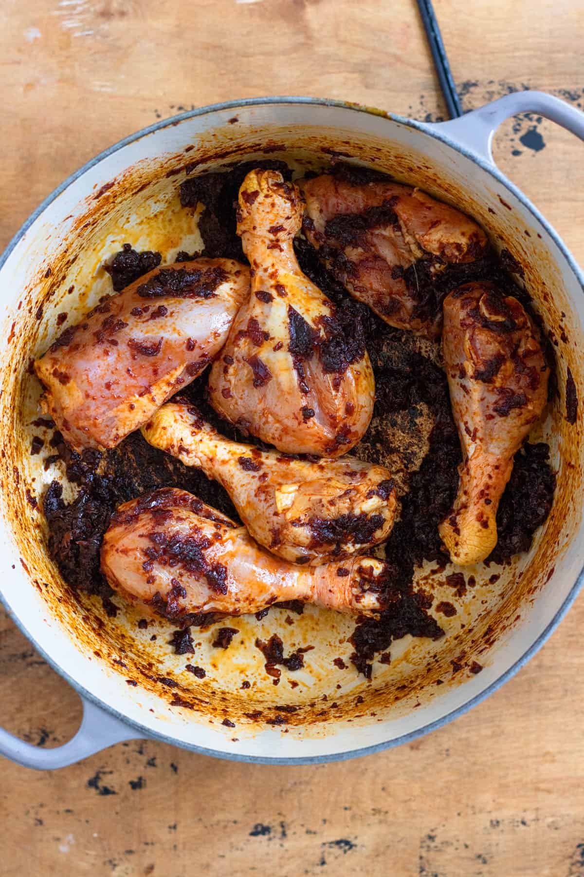 Chicken pieces in a pot coated with a rich onion mixture.
