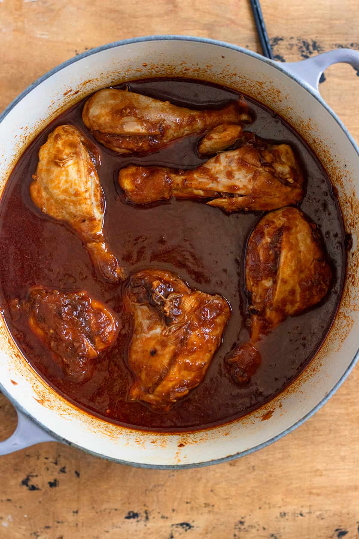 Chicken simmering in a pot with added broth.