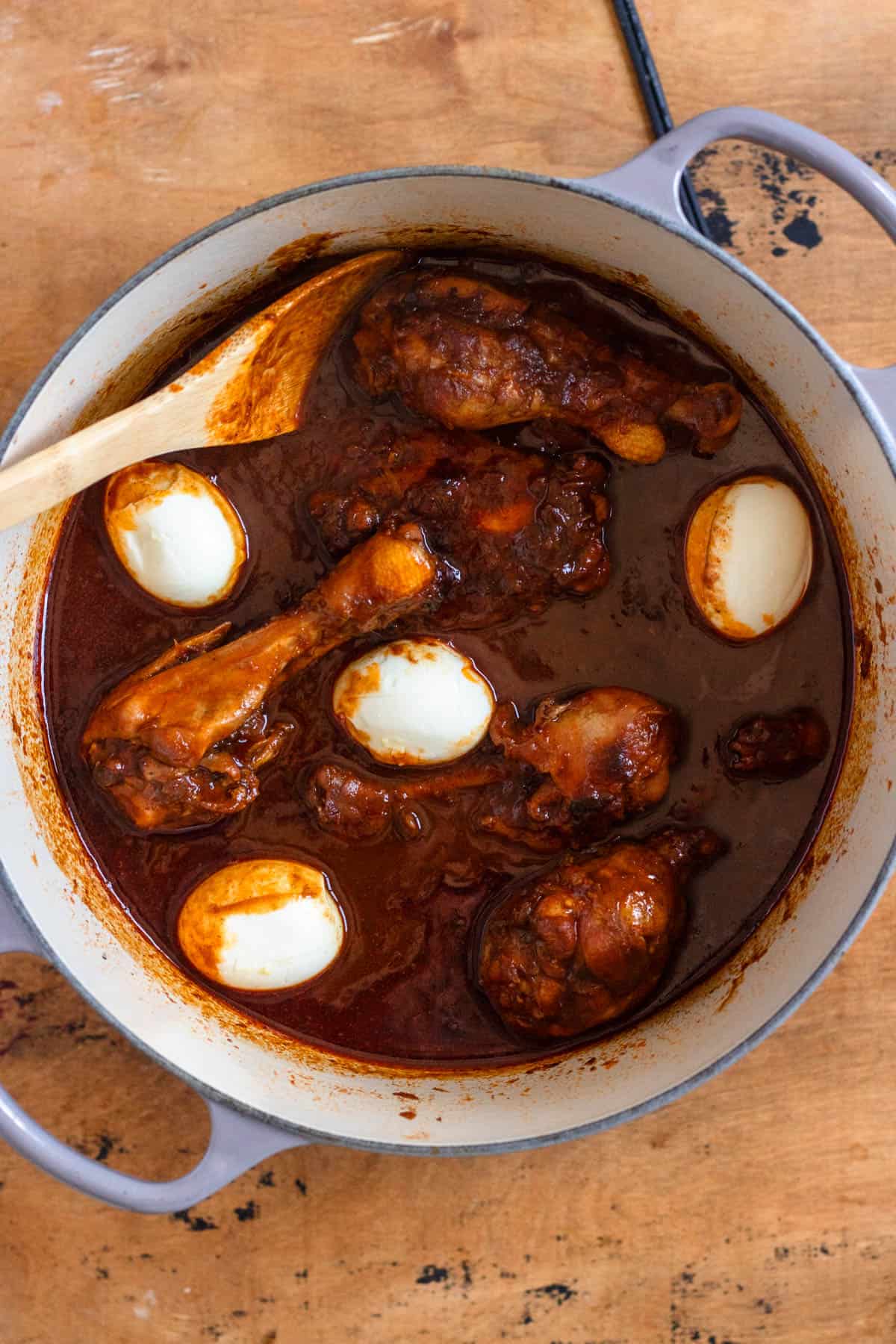 Boiled eggs being added to the pot with the simmering chicken.